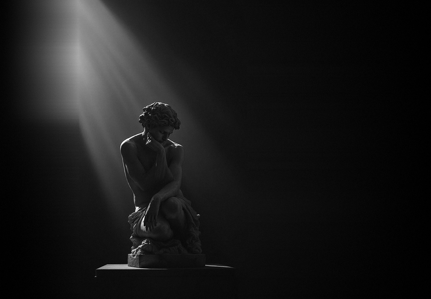 A marble sculpture sitting in thought, lit by a single shaft of light in deep shadow